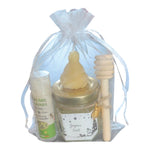 Cadeau de fin d'année artisanal avec miel, baume à lèvres et bougie en cire d'abeille présenté dans un sachet cadeau personnalisé.