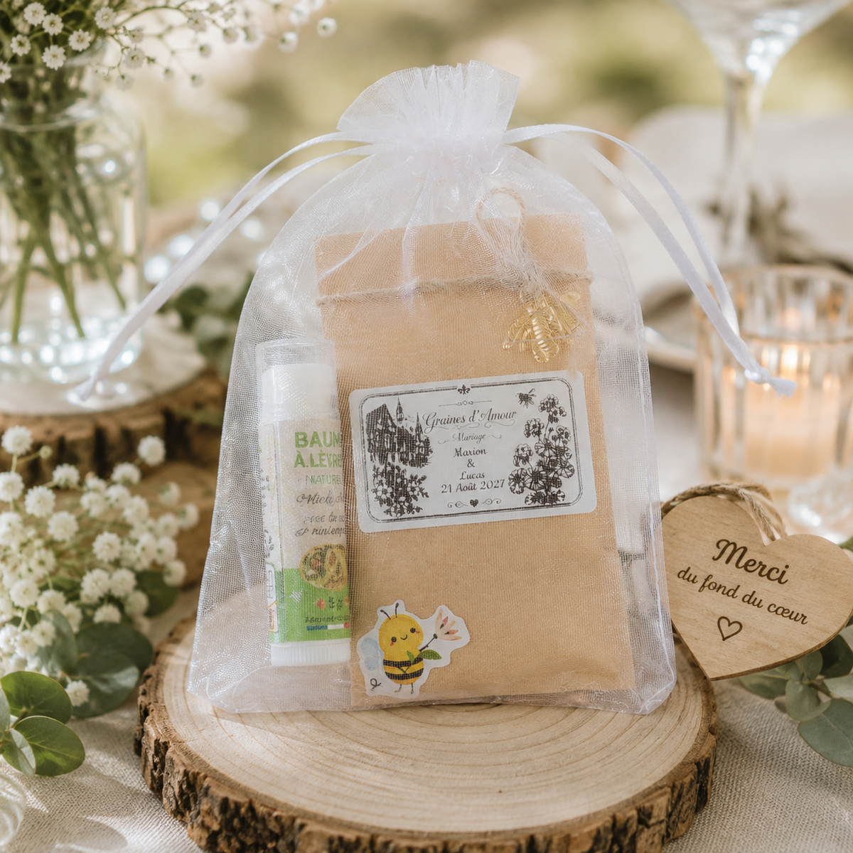 Cadeau invité mariage personnalisé avec sachet de graines Graines d'Amour, baume à lèvres artisanal à la cire d'abeille et pochon en organza, présenté dans une décoration de mariage champêtre.