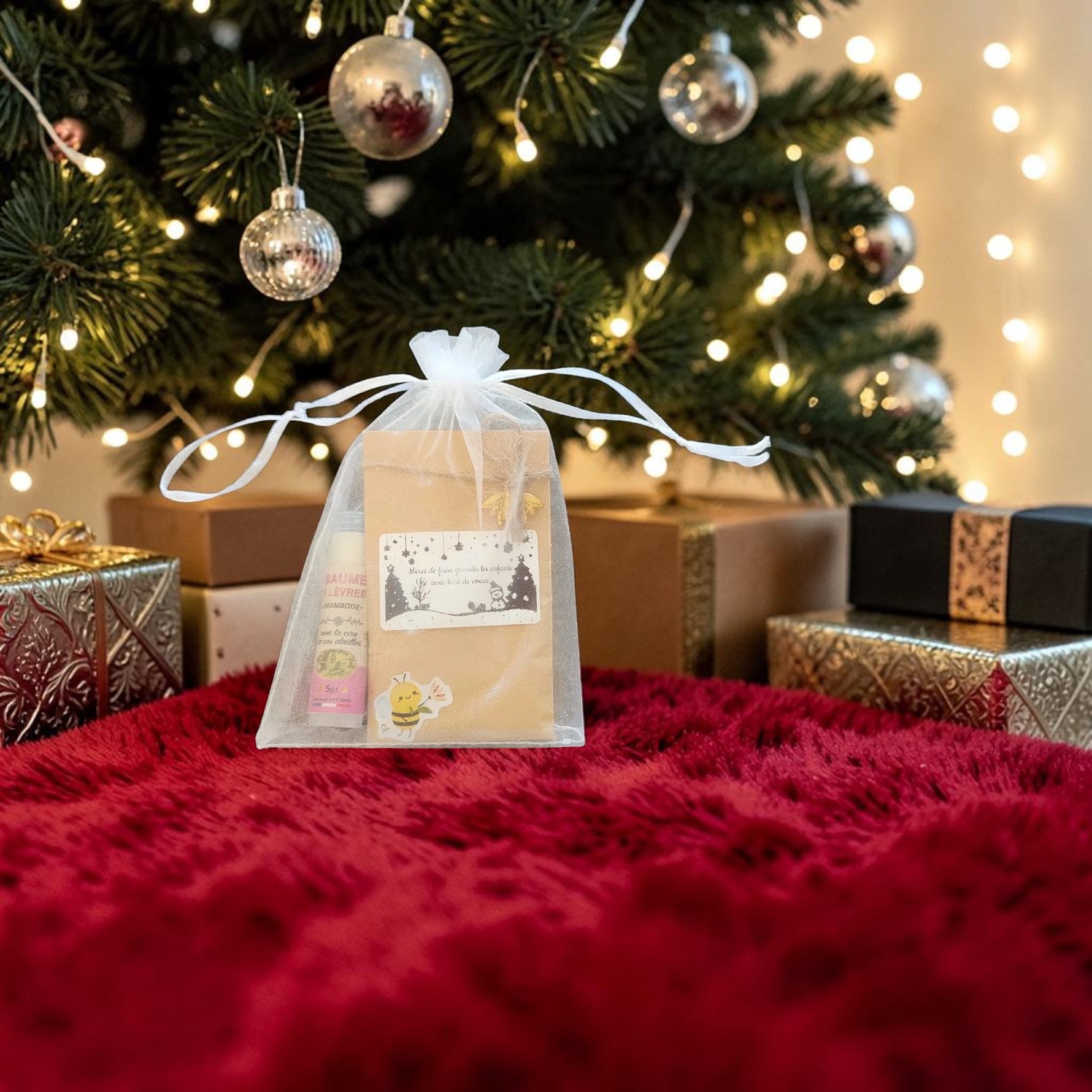Cadeau de Noël personnalisé présenté sous un sapin de Noël avec sachet de graines à étiquette personnalisable et baume à lèvres artisanal à la cire d'abeille de nos ruches.