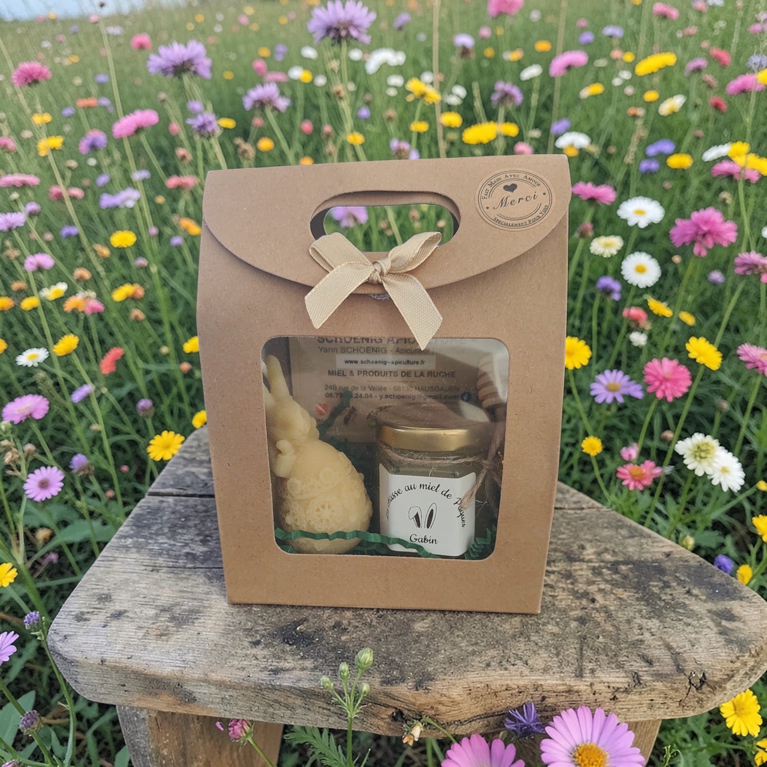 Coffret cadeau artisanal avec miel et bougie naturel, présenté en extérieur dans un décor fleuri, parfait pour un cadeau écologique et authentique.