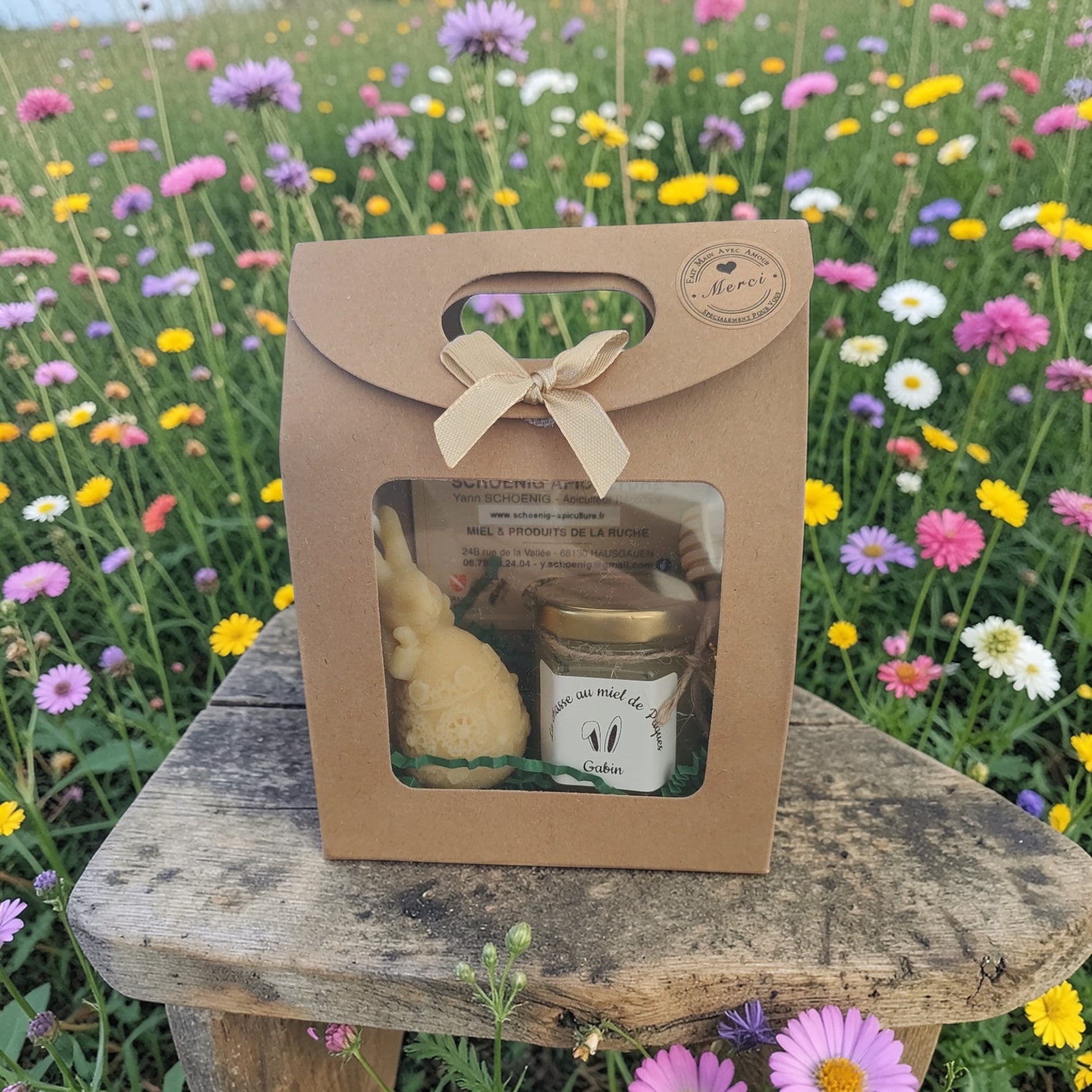 Coffret cadeau artisanal avec miel et bougie naturel, présenté en extérieur dans un décor fleuri, parfait pour un cadeau écologique et authentique.