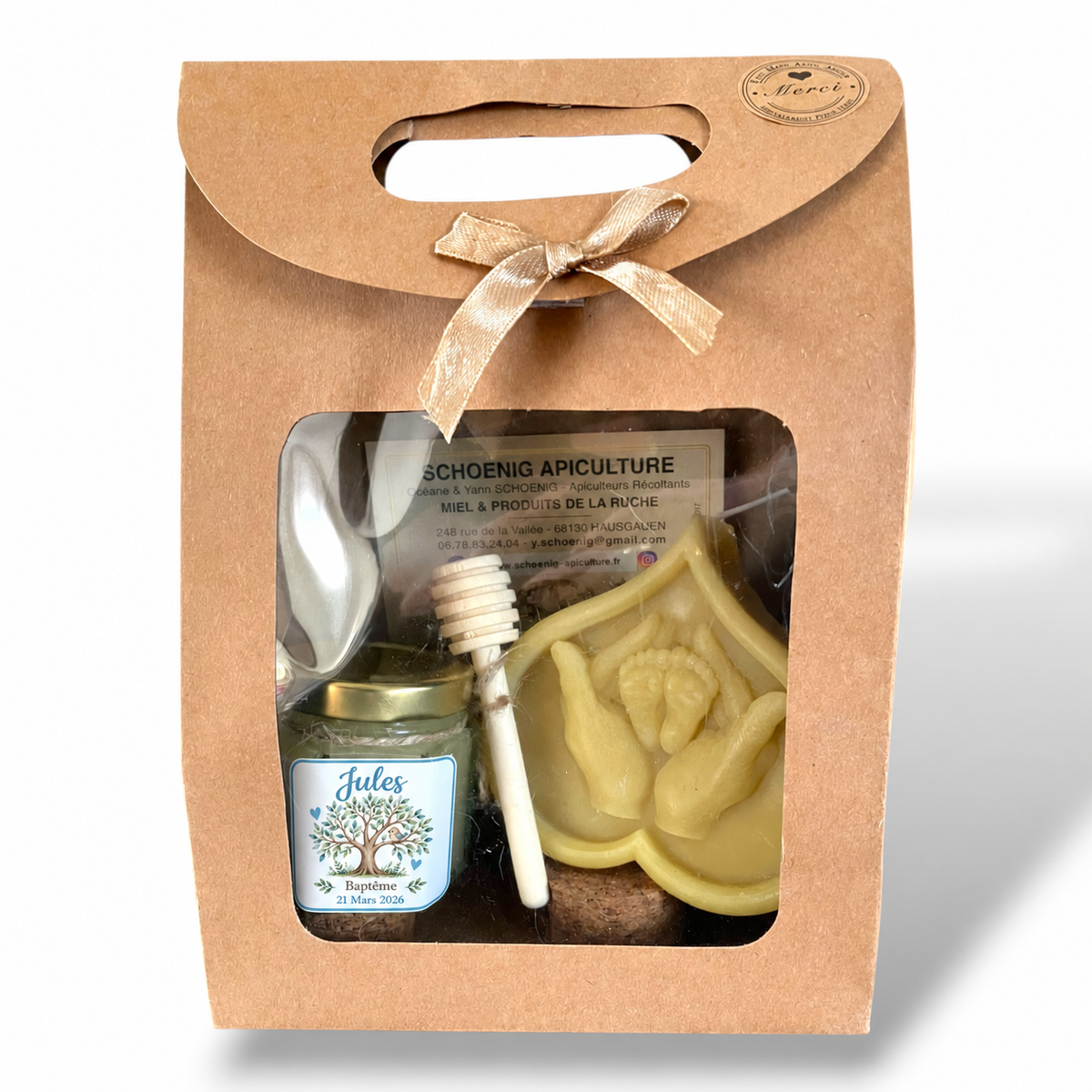 Coffret cadeau de baptême personnalisé pour garçon avec miel artisanal, bougie en cire d’abeille représentant des mains tenant les pieds d’un bébé et cuillère à miel.