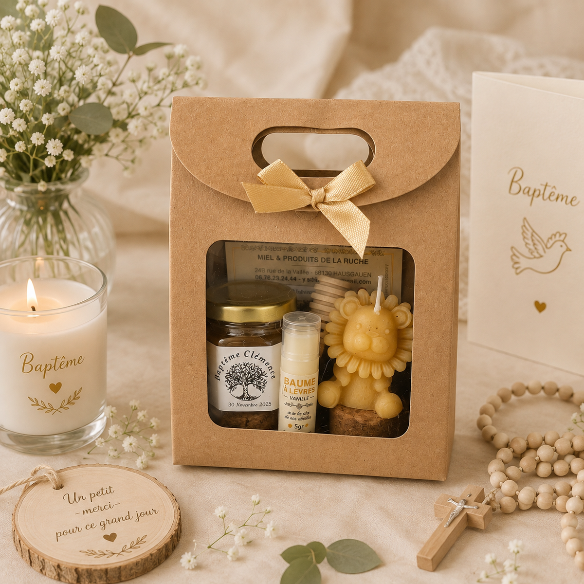 Coffret cadeau invité baptême personnalisé avec miel artisanal, baume à lèvres, bougie lion en cire d'abeille et étiquette personnalisée, présenté dans une décoration élégante de baptême.