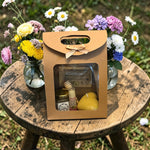 Coffret cadeau naturel avec miel, baume à lèvres et bougie en cire d’abeille présenté avec des fleurs idée cadeau bonne fête fête