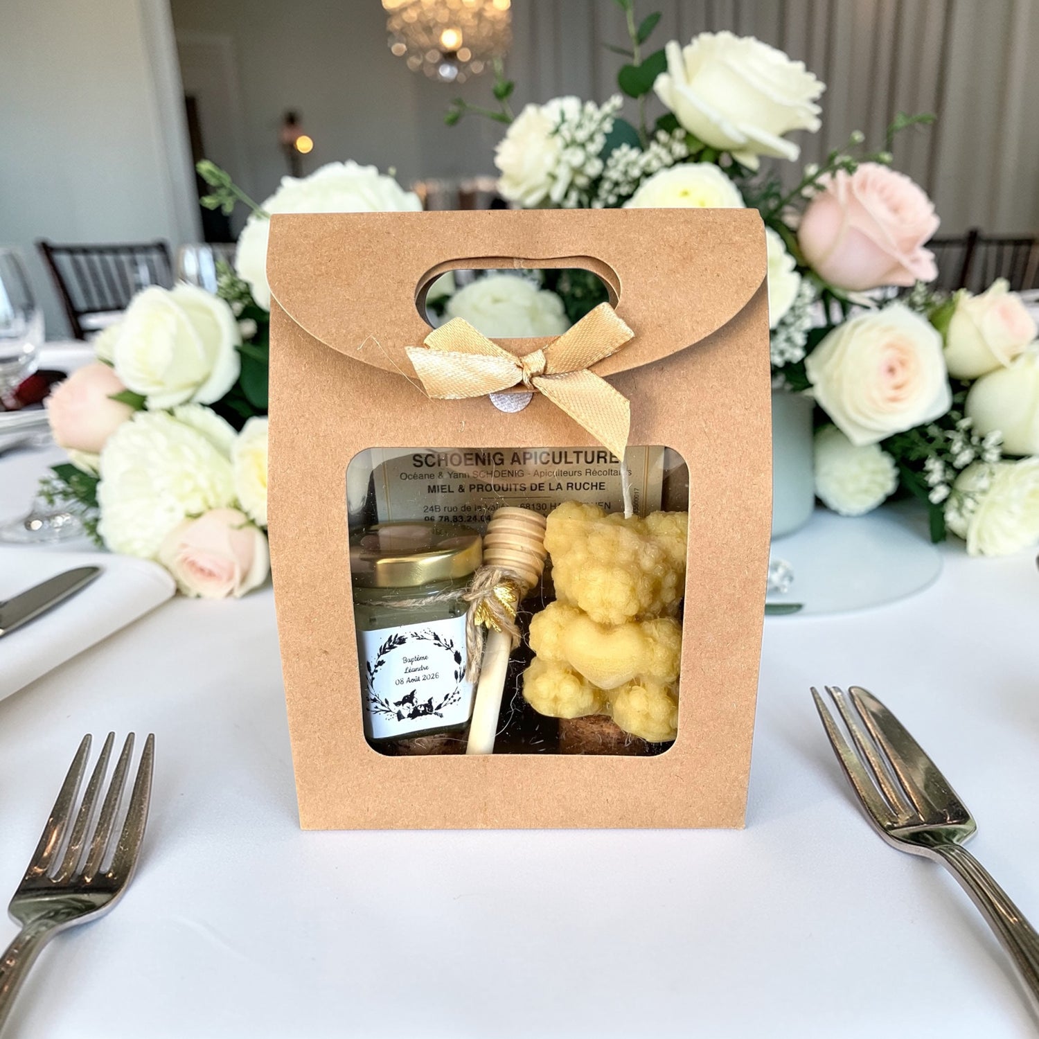 Idée cadeau invité baptême sur table décorée avec fleurs, coffret miel personnalisé et bougie abeille parfait pour baby shower ou naissance