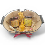 Panier cadeau artisanal avec miel naturel, bougie en cire d’abeille et baume à lèvres, présenté dans un panier rustique, idée cadeau authentique et écologique.